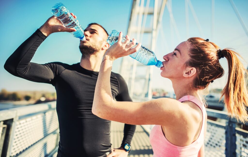 couple drinking water from a bottle after exercising
