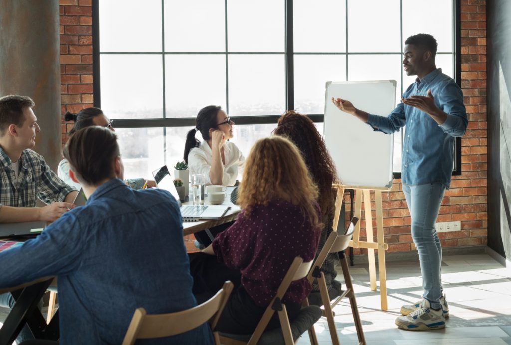 Team leader is lecturing his employees in loft office using white board, copy space