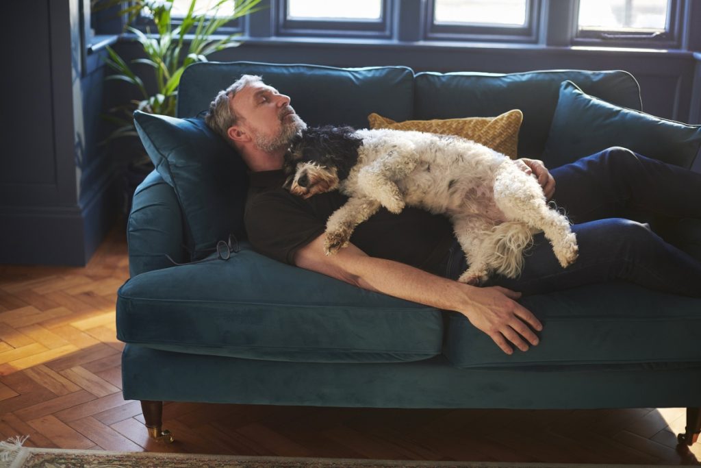 caucassian man sleeping in the couch with his dog