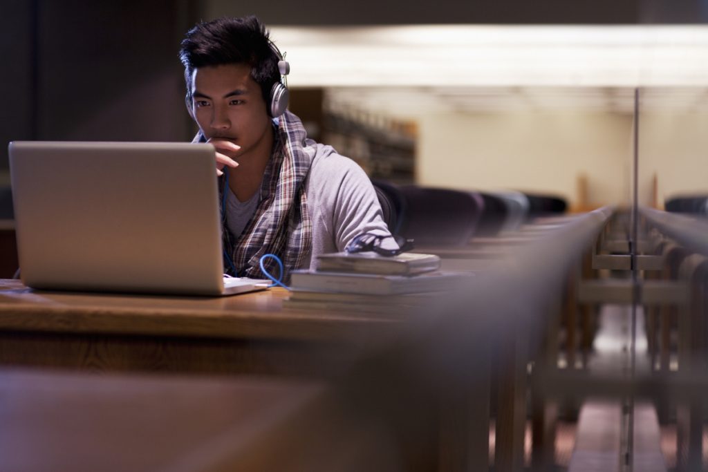 Student focused working on laptop in library