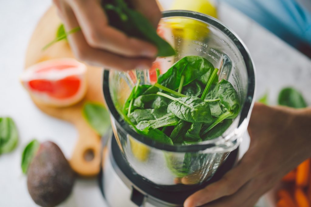 Cooking healthy detox smoothie with fresh fruits and green spinach.