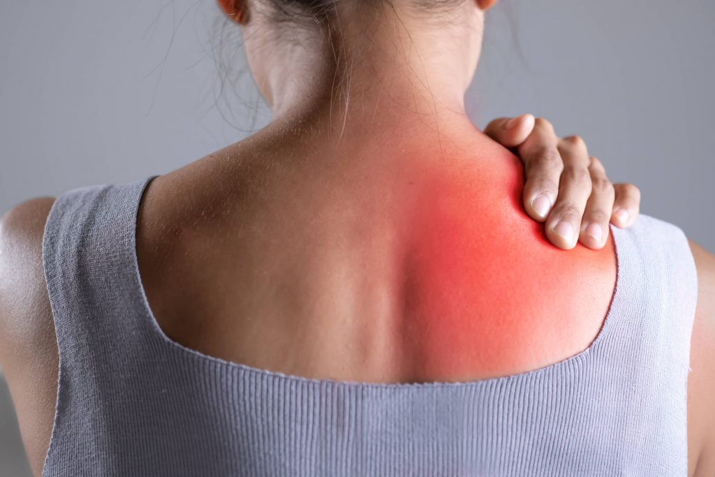 Female holding painful shoulder with another hand.